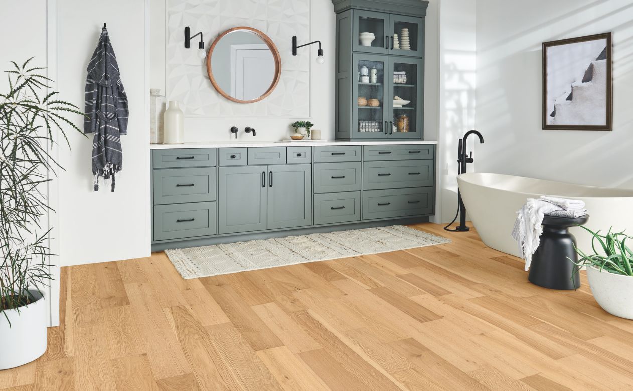 waterproof wood look flooring in a stylish bathroom with grey cabinets and tub