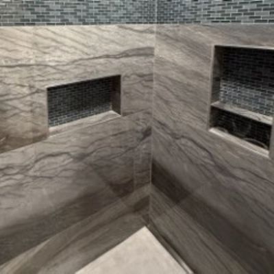 grey wall shower with blue and grey mosaic tiles in niche